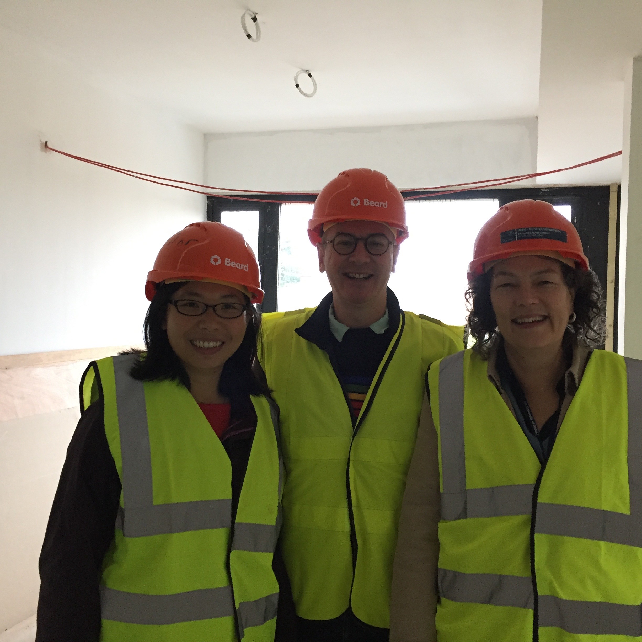 Three people wearing hard hats and hi-vis smiling at the camera