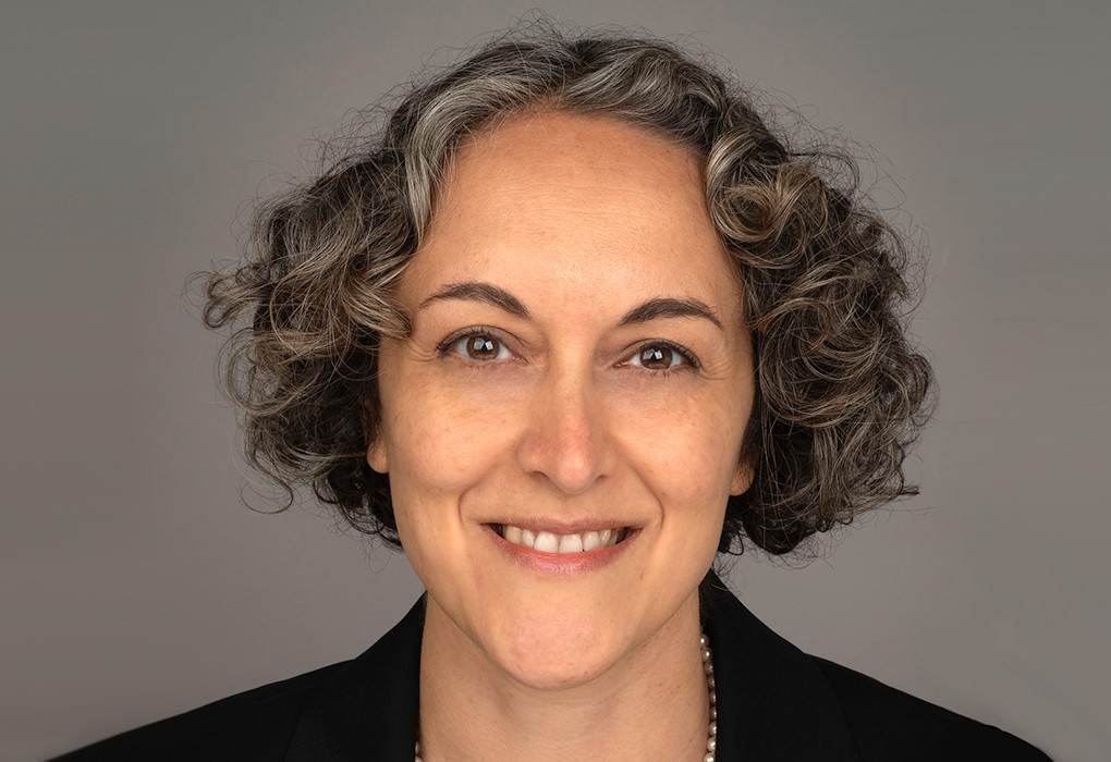 A lady smiling at the camera with short curly hair