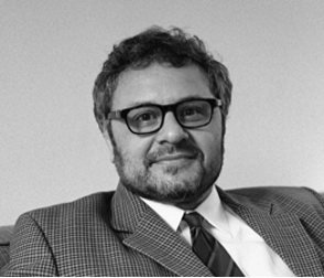 A black-and-white photo of Michael Santoro, pictured here in glasses and a suit.