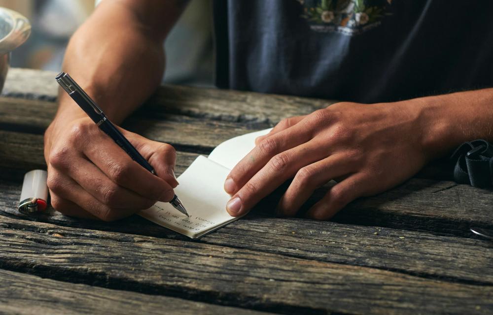 Person writing in notebook (showing hands only)