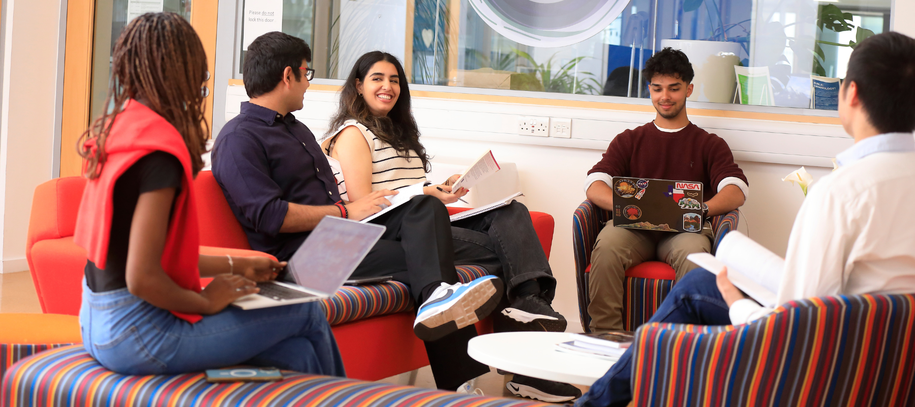 Students having an academic discussion on sofas inside the Faculty of Law