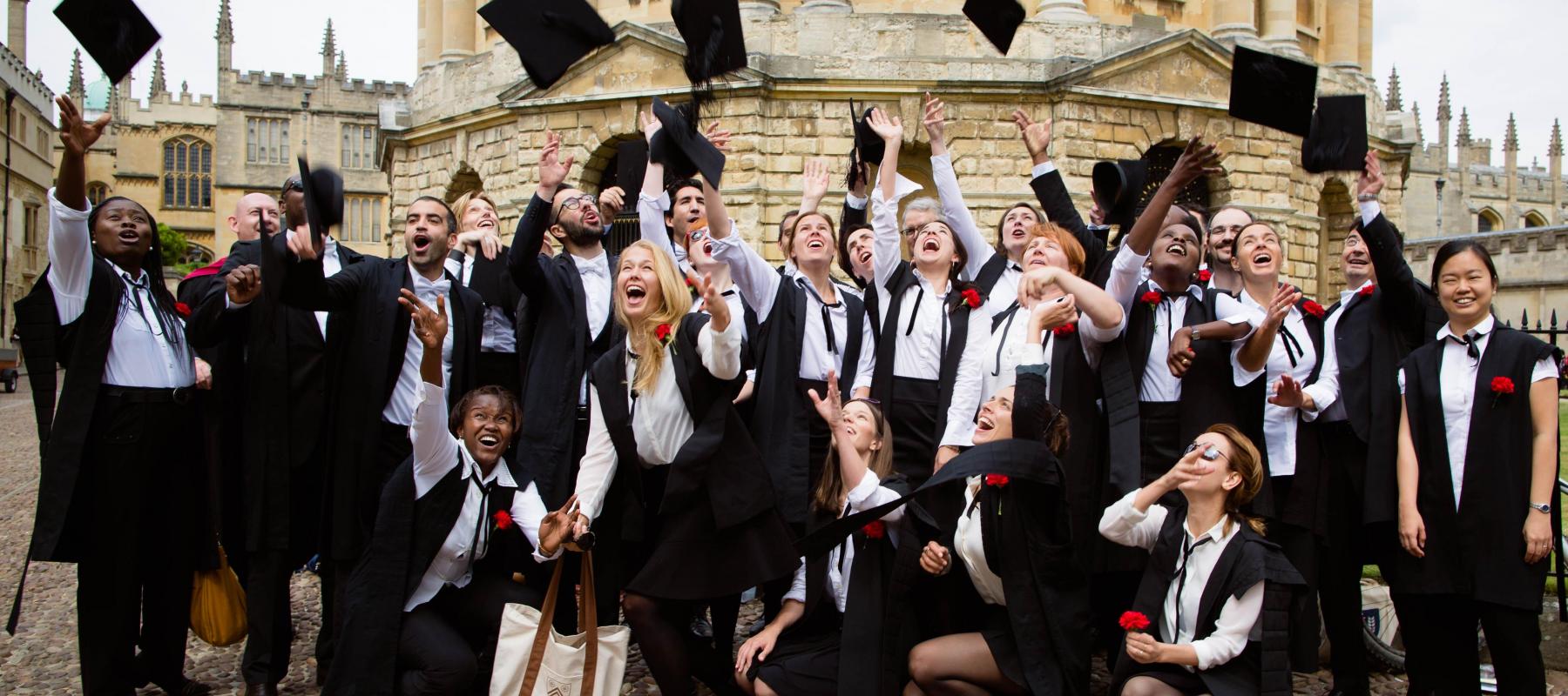 A group of students in academic dress celebrate receiving their degree