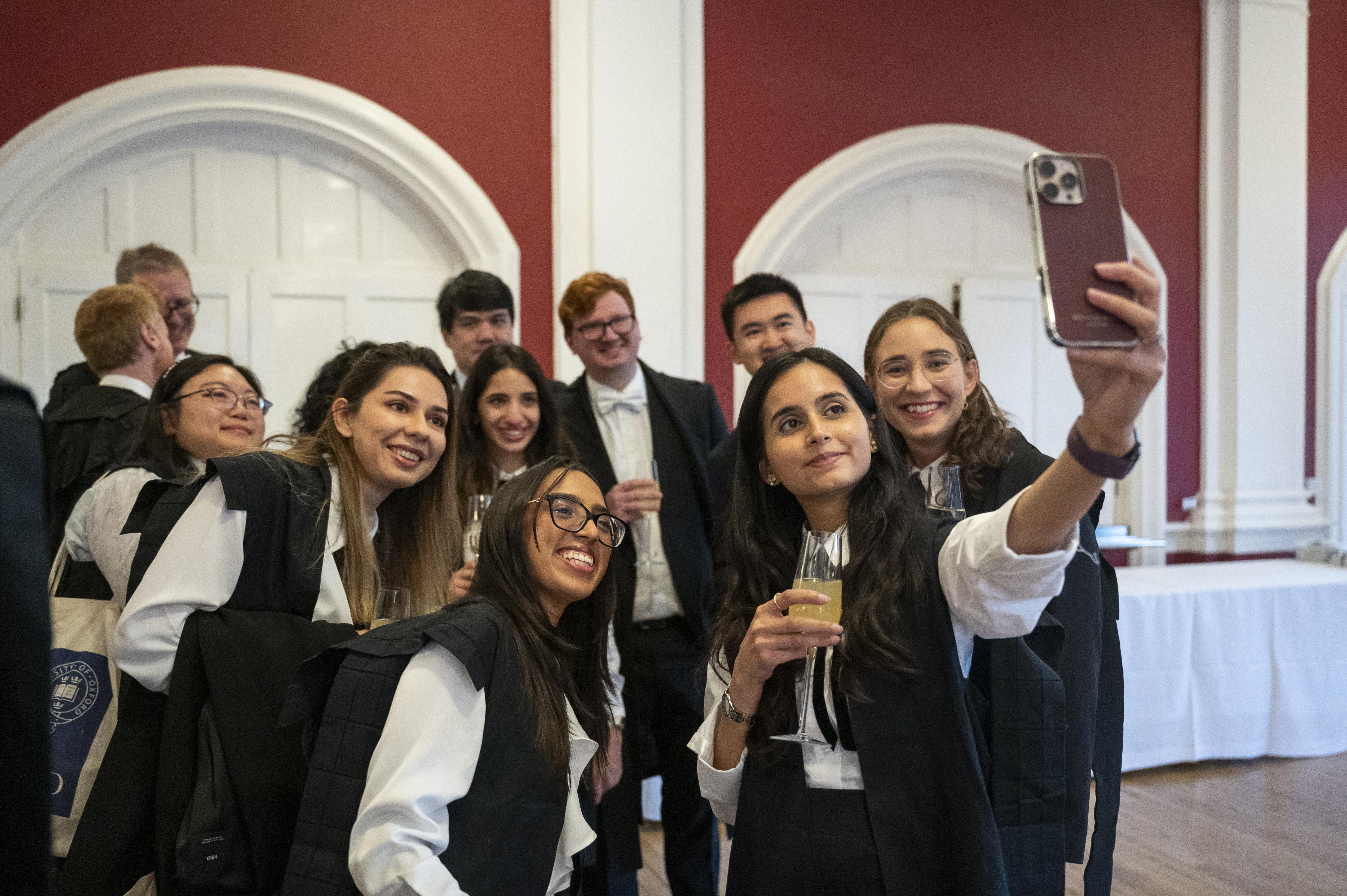Group of students taking a selfie in sub fusc in St Hugh's Dining Hall