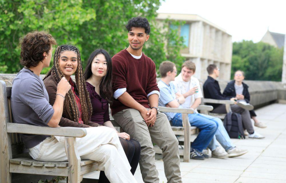 Students sitting on benches outside the St Cross Building