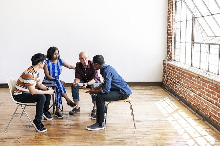 Four people sitting around in a semi-circle discussing