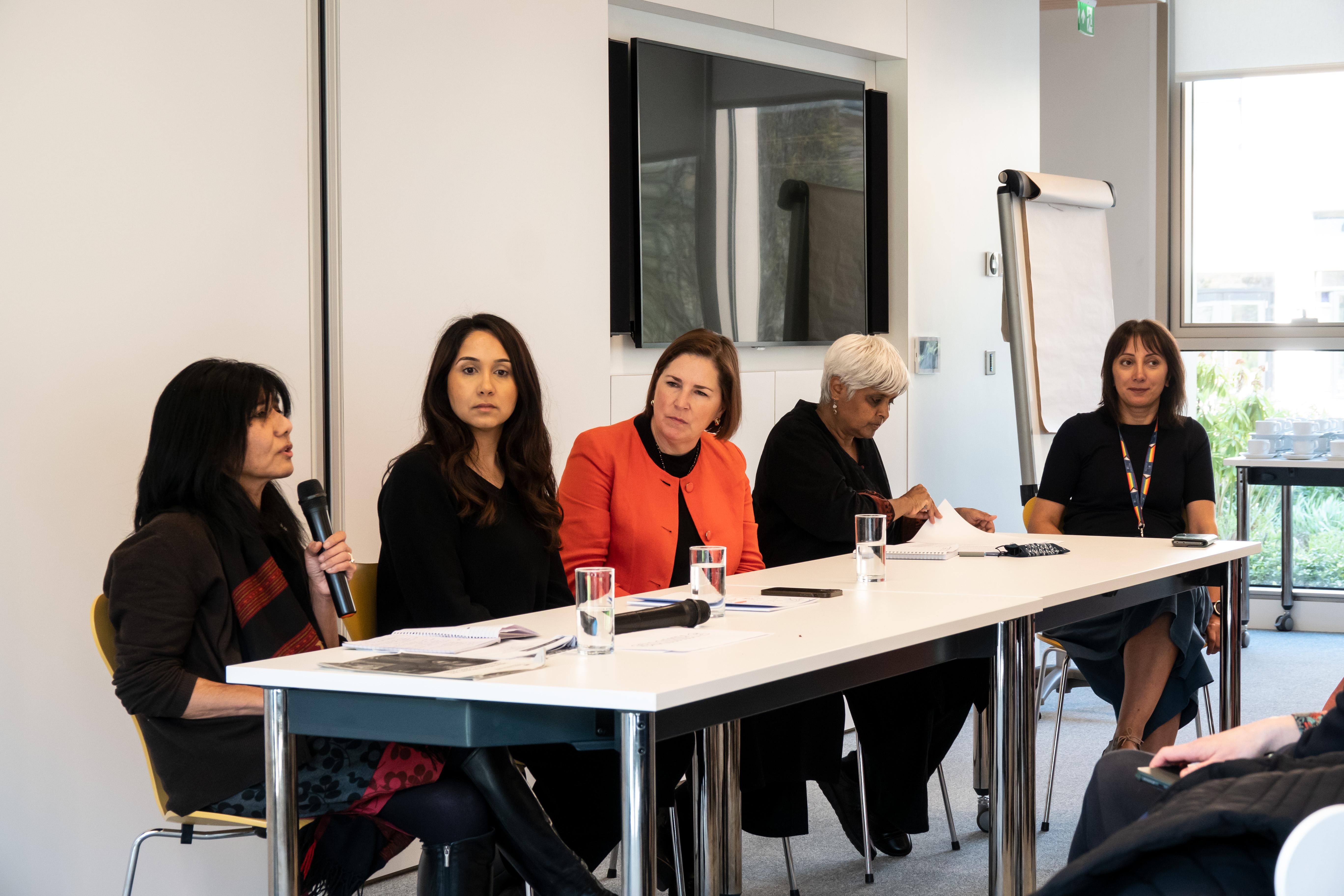 Panel of 5 women sitting behind a white table