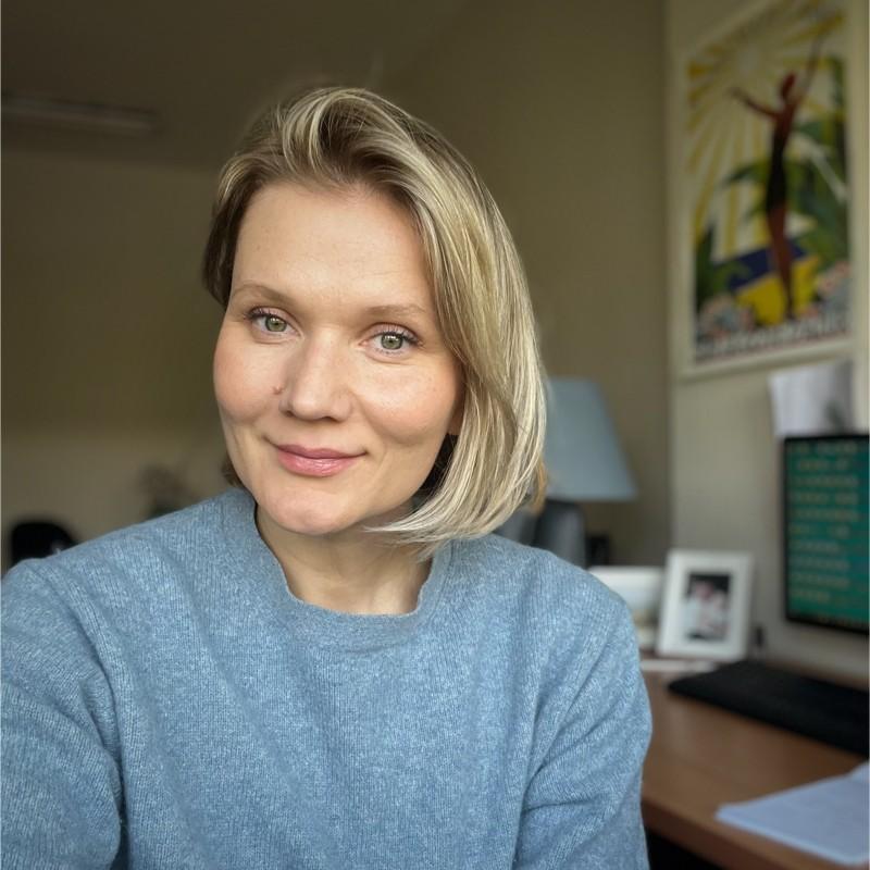 Hanna wearing a blue-grey jumper and smiling into the camera