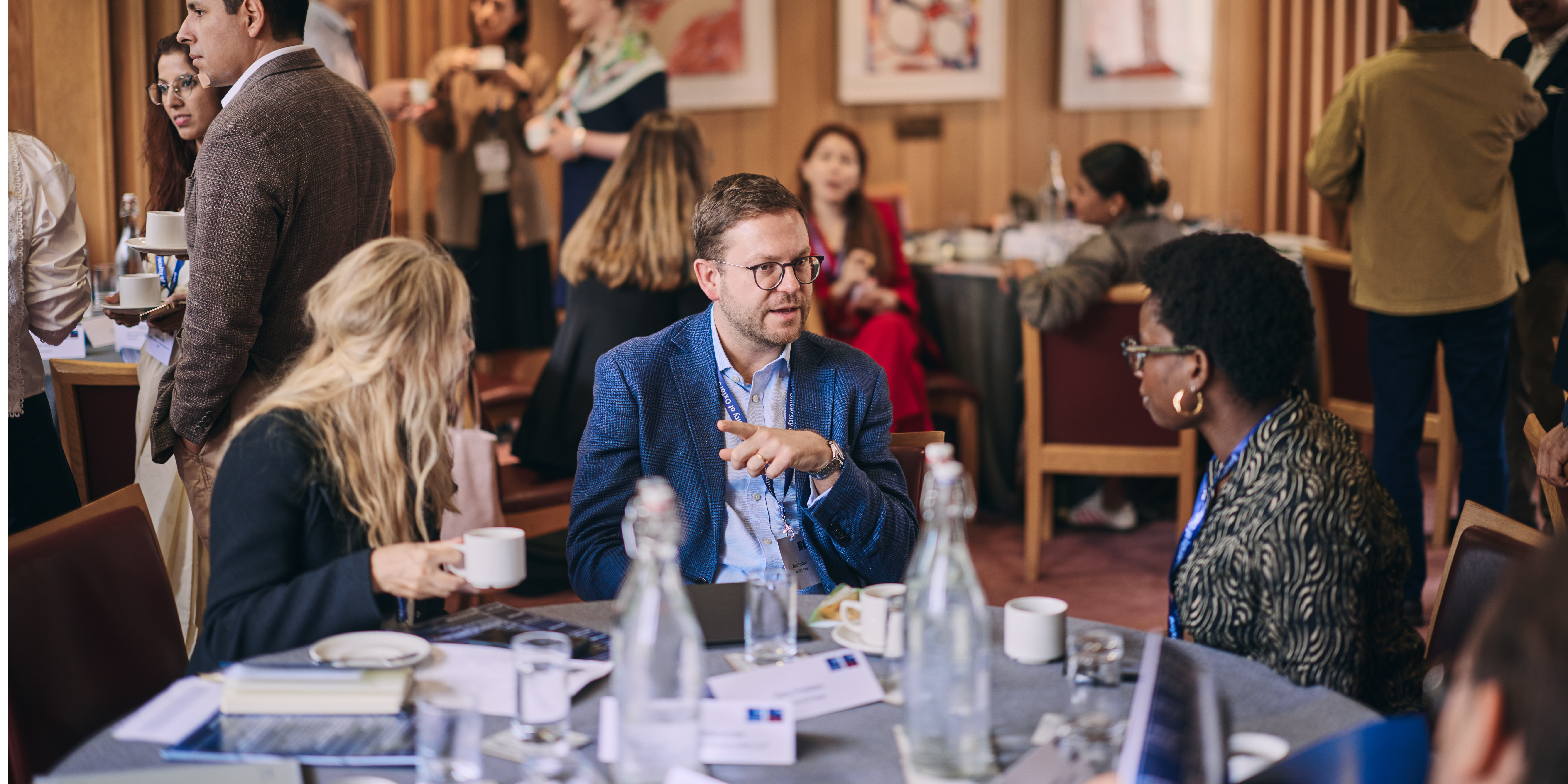 Discussion between 3 participants at a table at a professional development programme at the University of Oxford
