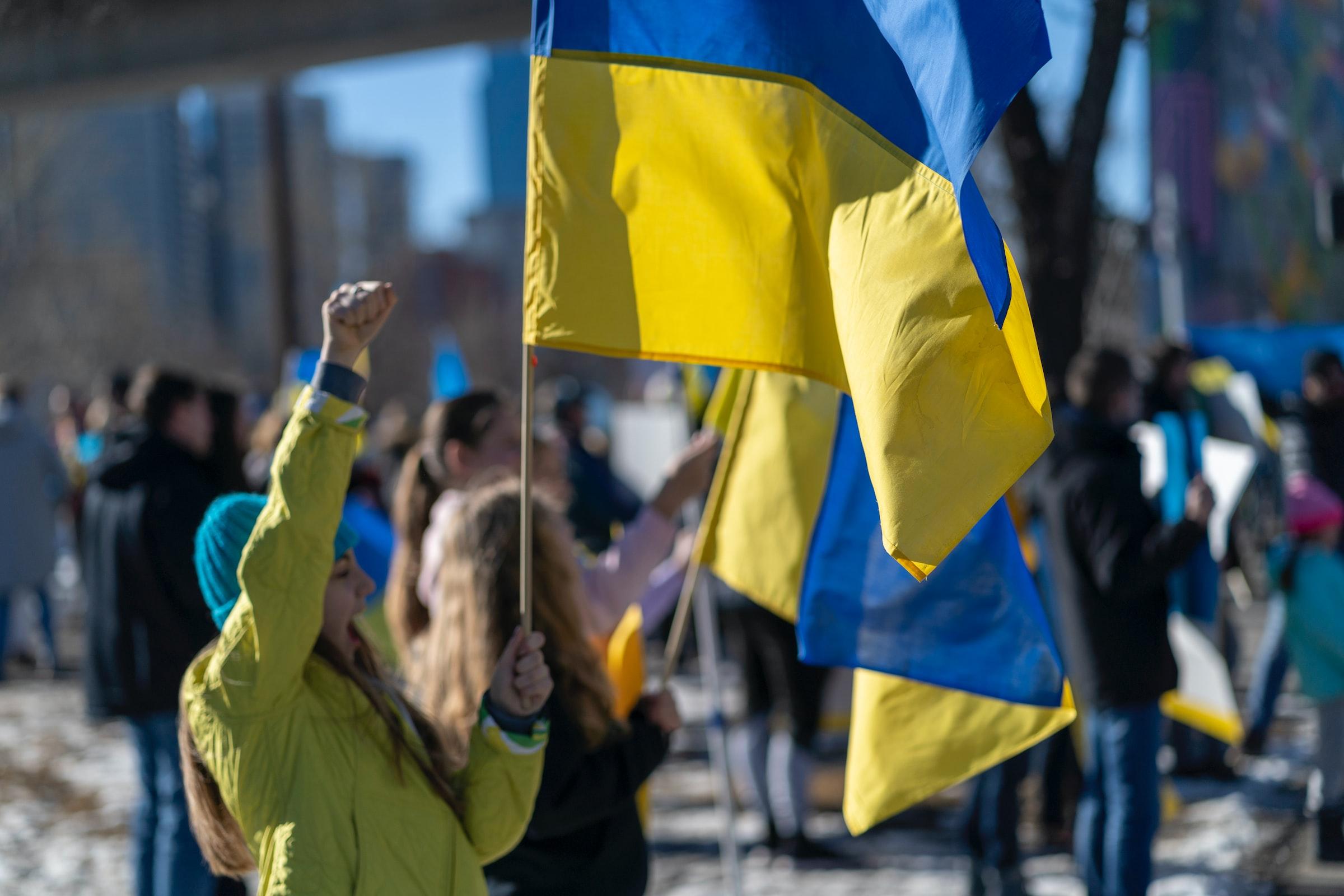 Image of a woman holding the Ukranian flag with her fist in the air