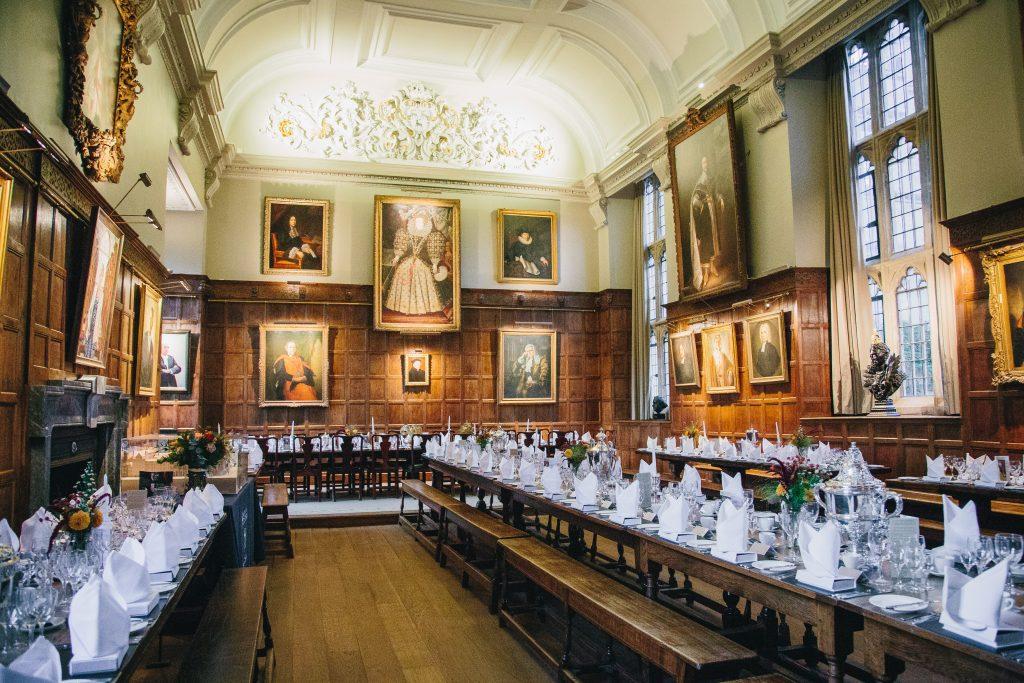 Jesus College Dining Hall - an oak panelled room with long hall tables dressed for dinner with napkins, cutlery and candles.