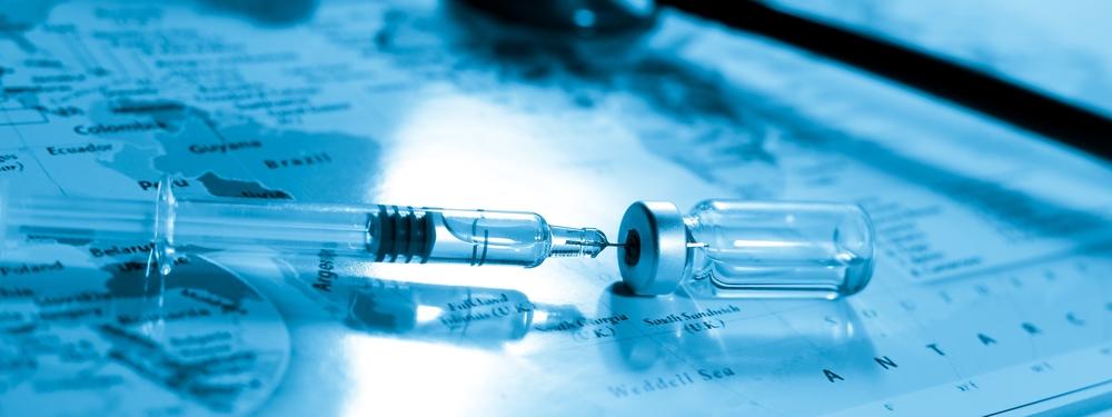 Injection needle and vial on a world map 