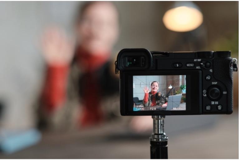 A woman recording a film using a camera and tripod.