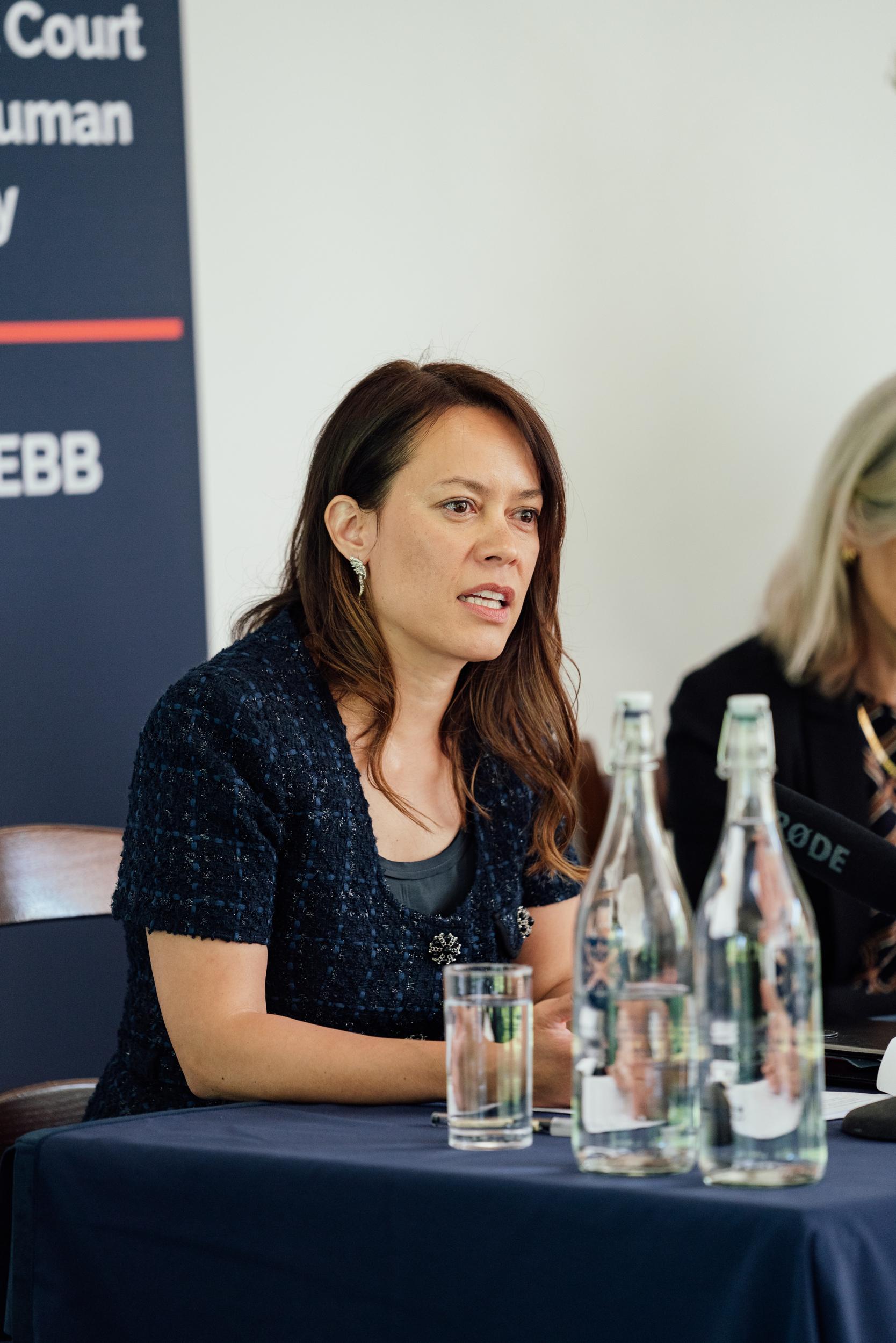 Philippa Webb seated at a table with bottles of water in front of her.