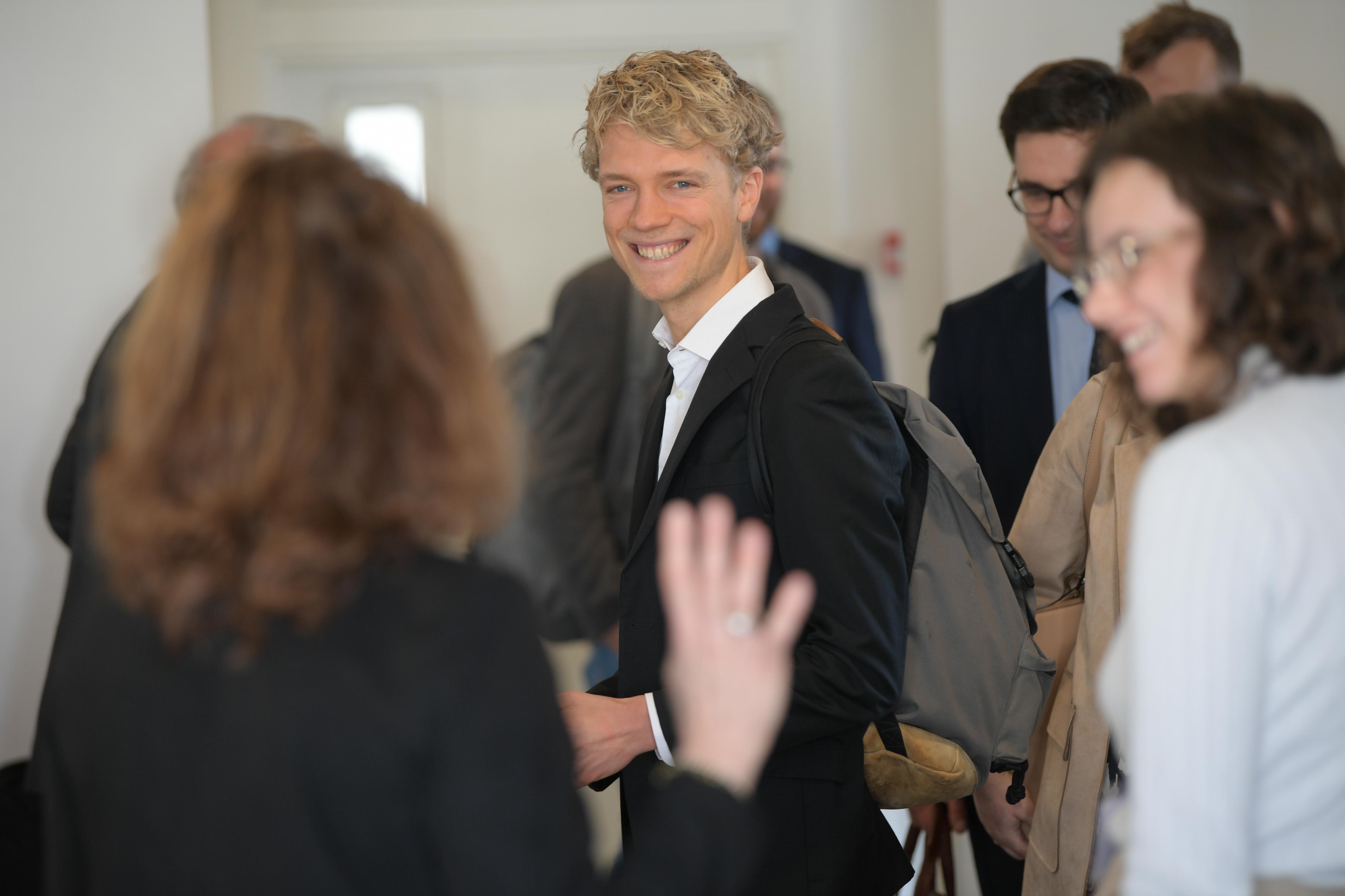 Alexander Wentker smiles as he walks through a crowd of people at a conference