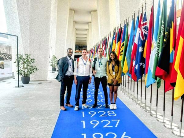 The iManage team (Halefom Abraha, Six Silberman, Sangh Rakshita and Aislinn Kelly-Lyth) at the ILO standing next to a row of flags