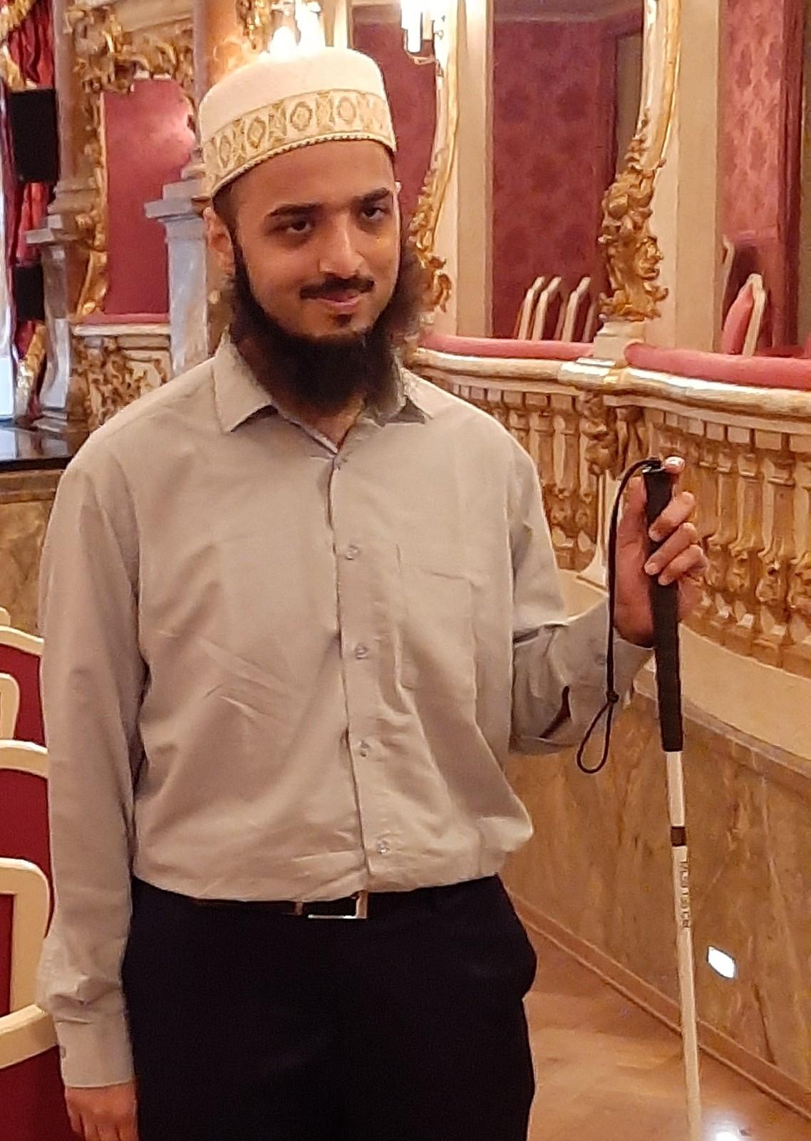 Moiz Tundawala - an Indian man with a turban and a beard holding a white stick