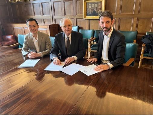 Three men sitting at a table with papers in front of them