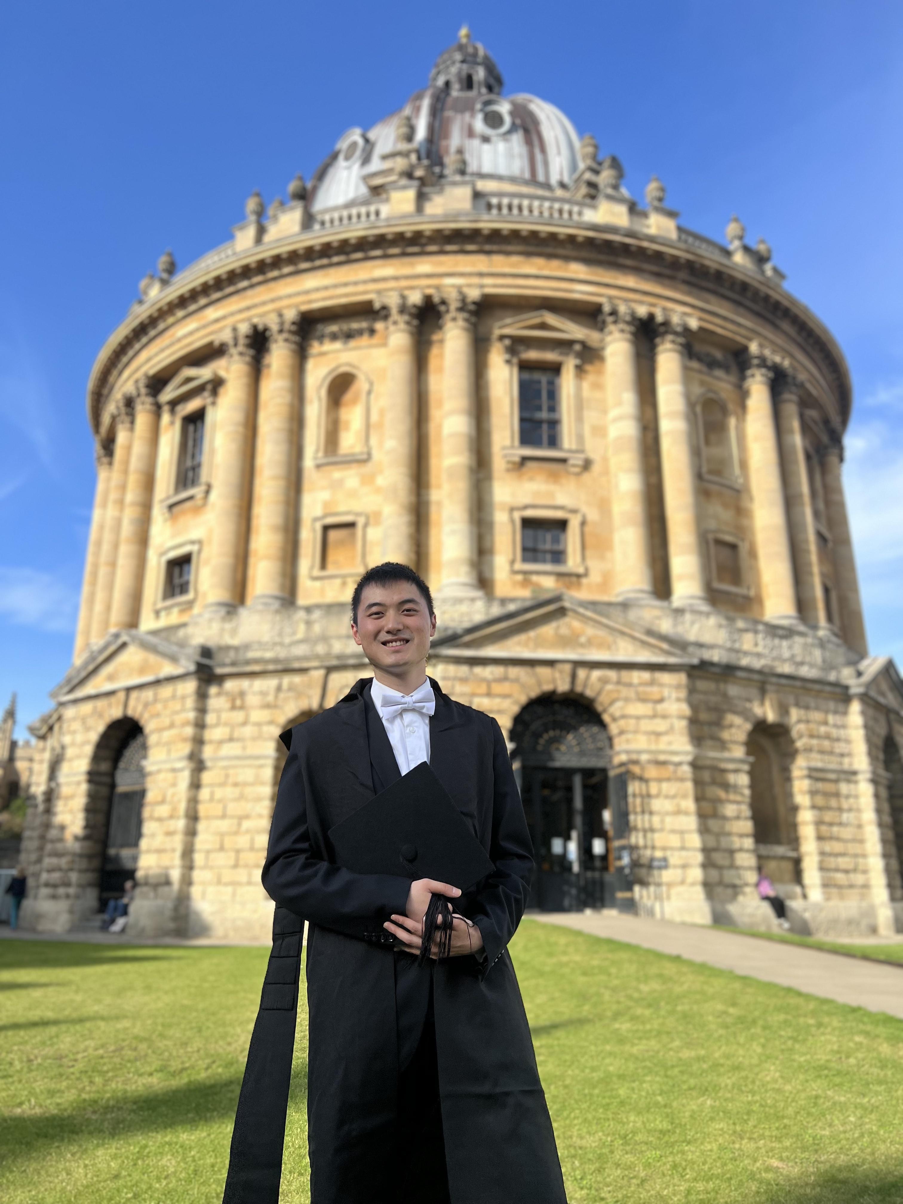 A man in sub-fusc standing in front of the Radcliffe Camera.