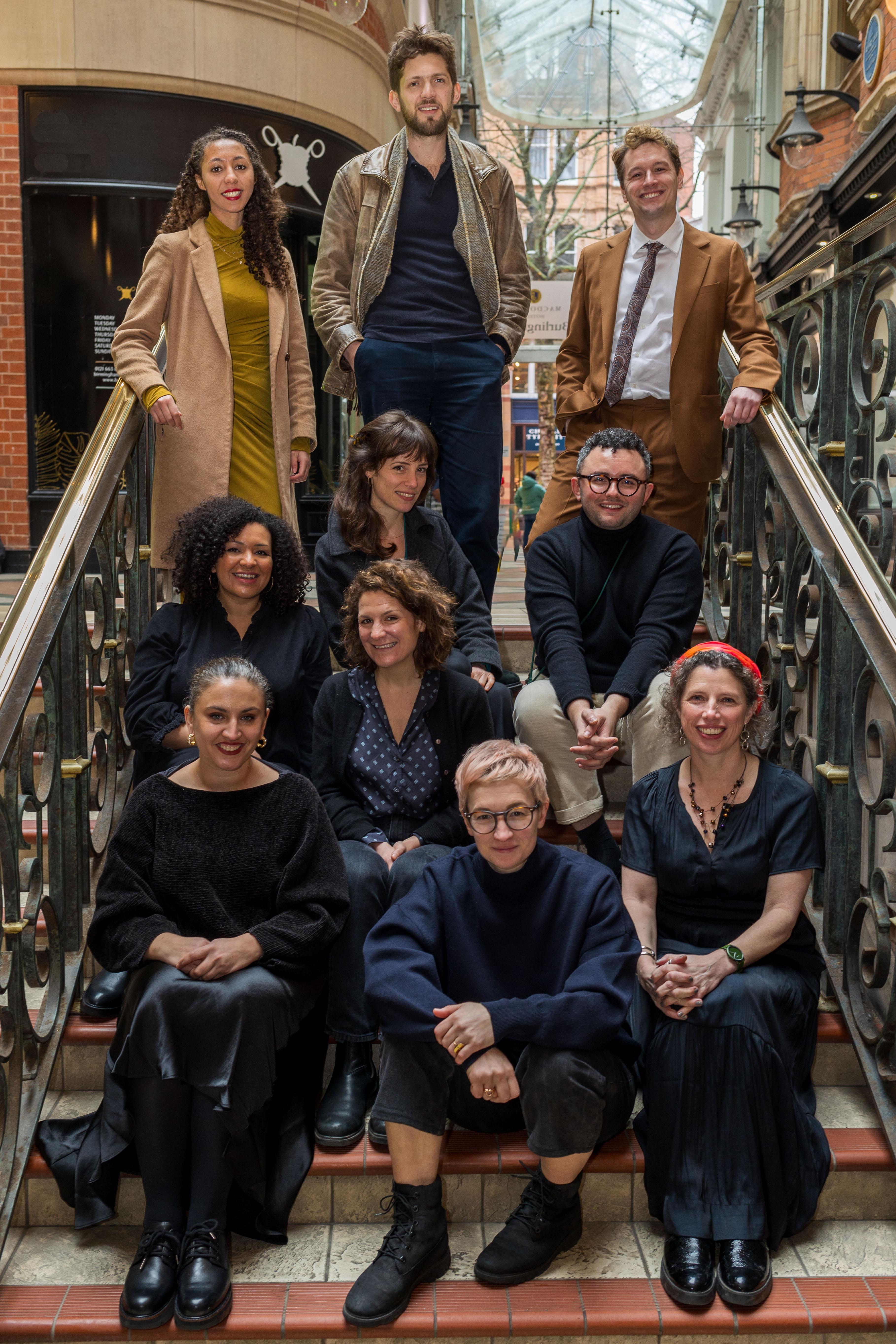 A group of 10 people standing and sitting on a flight of ornate stairs