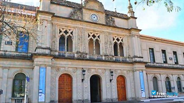 Large imposing old building in Argentina, with flags hanging from masts outside the entrance.