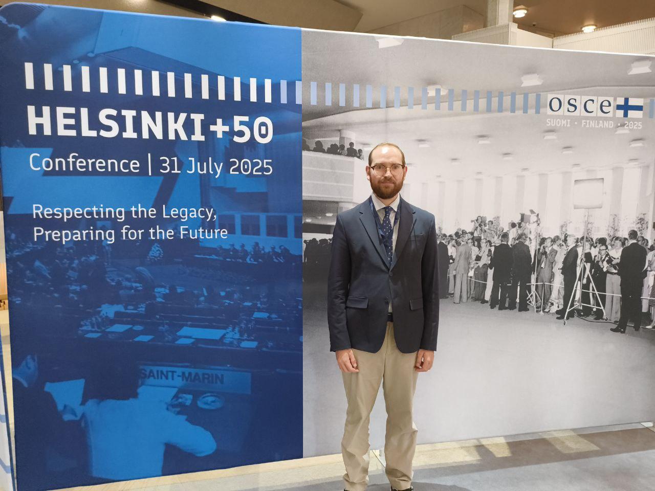 Photo of Denis by an event poster