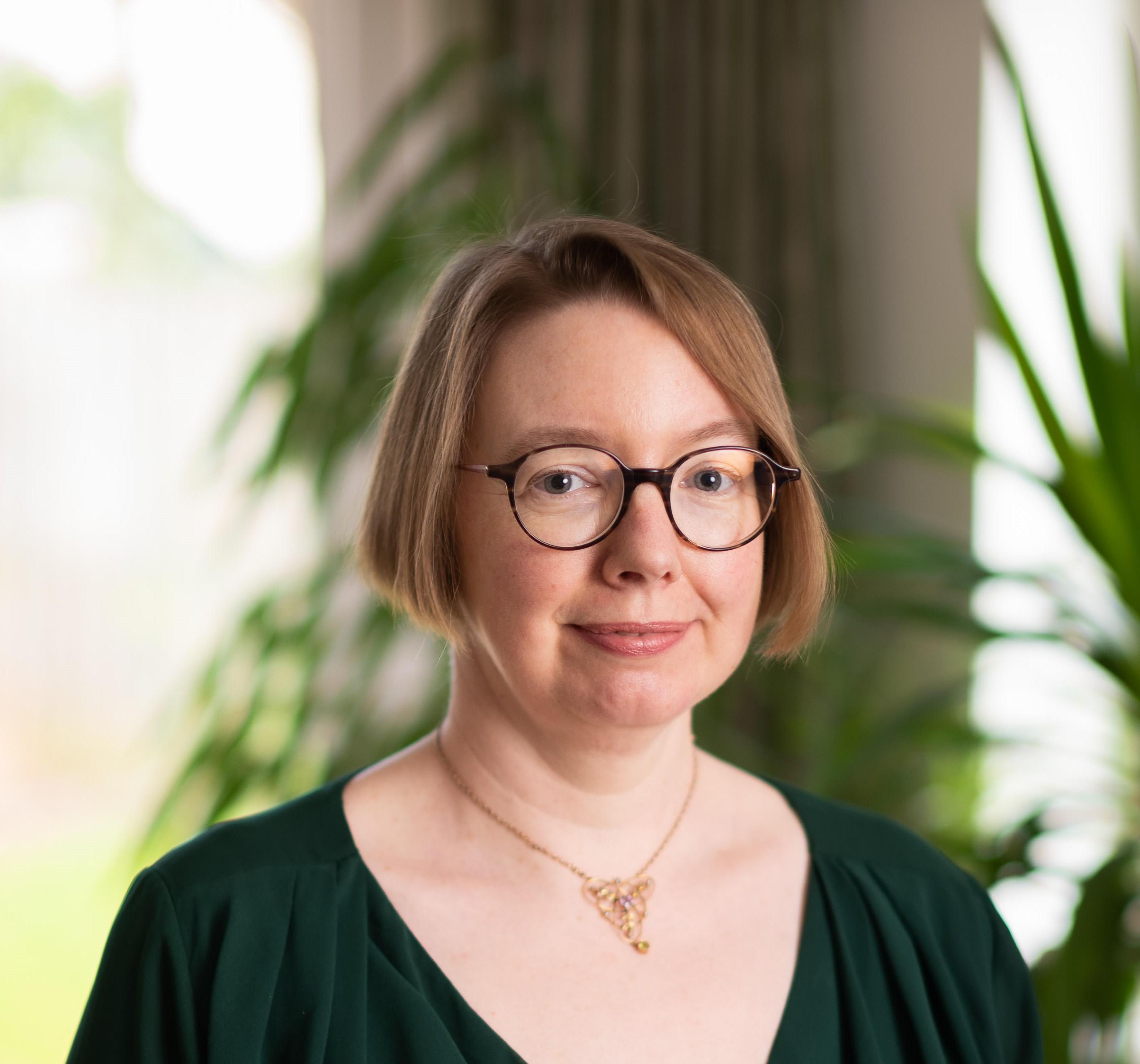Headshot of Anne Davis in a black blouse and gold necklace