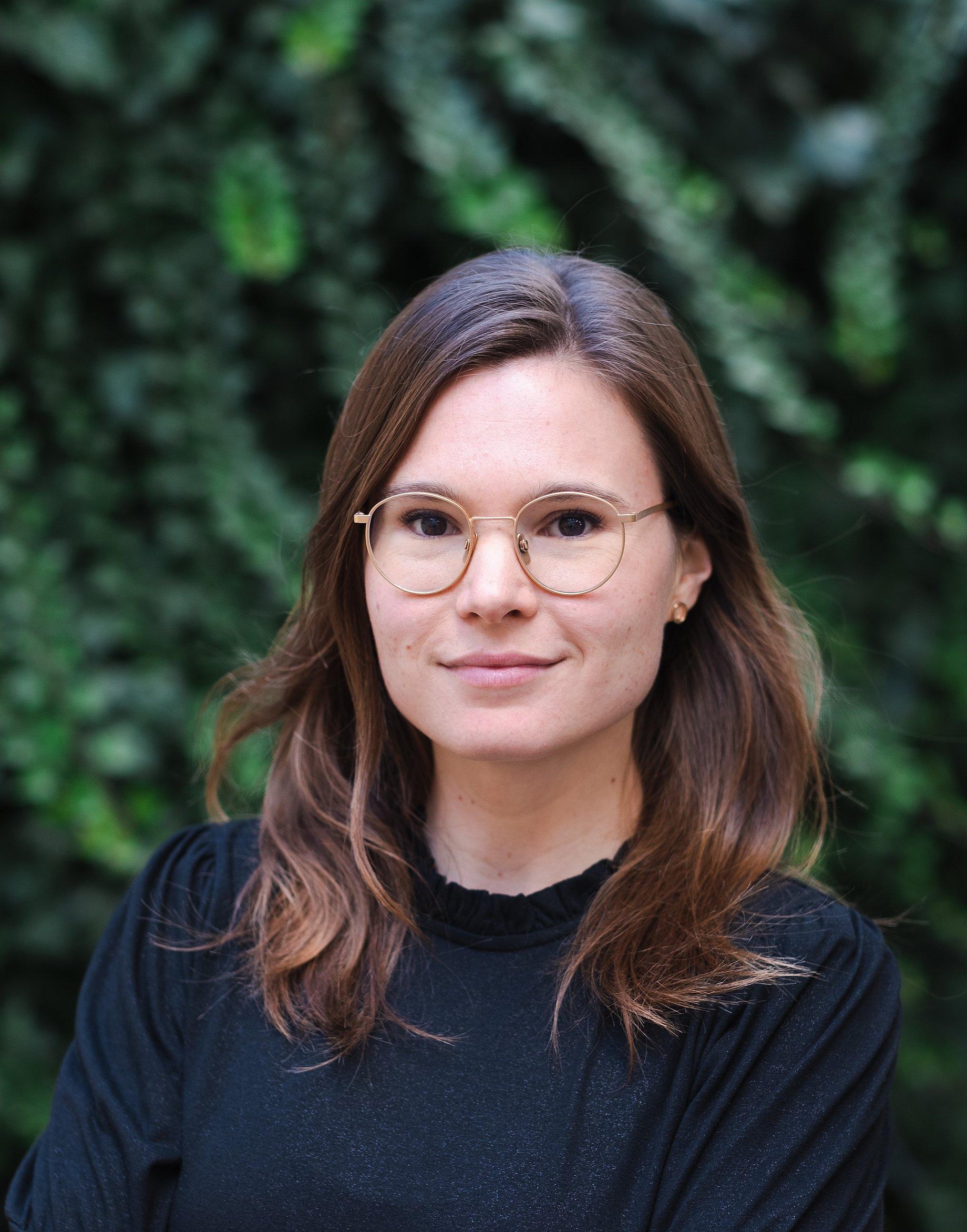 Corina Heri in a black jumper with blurred foliage in the background