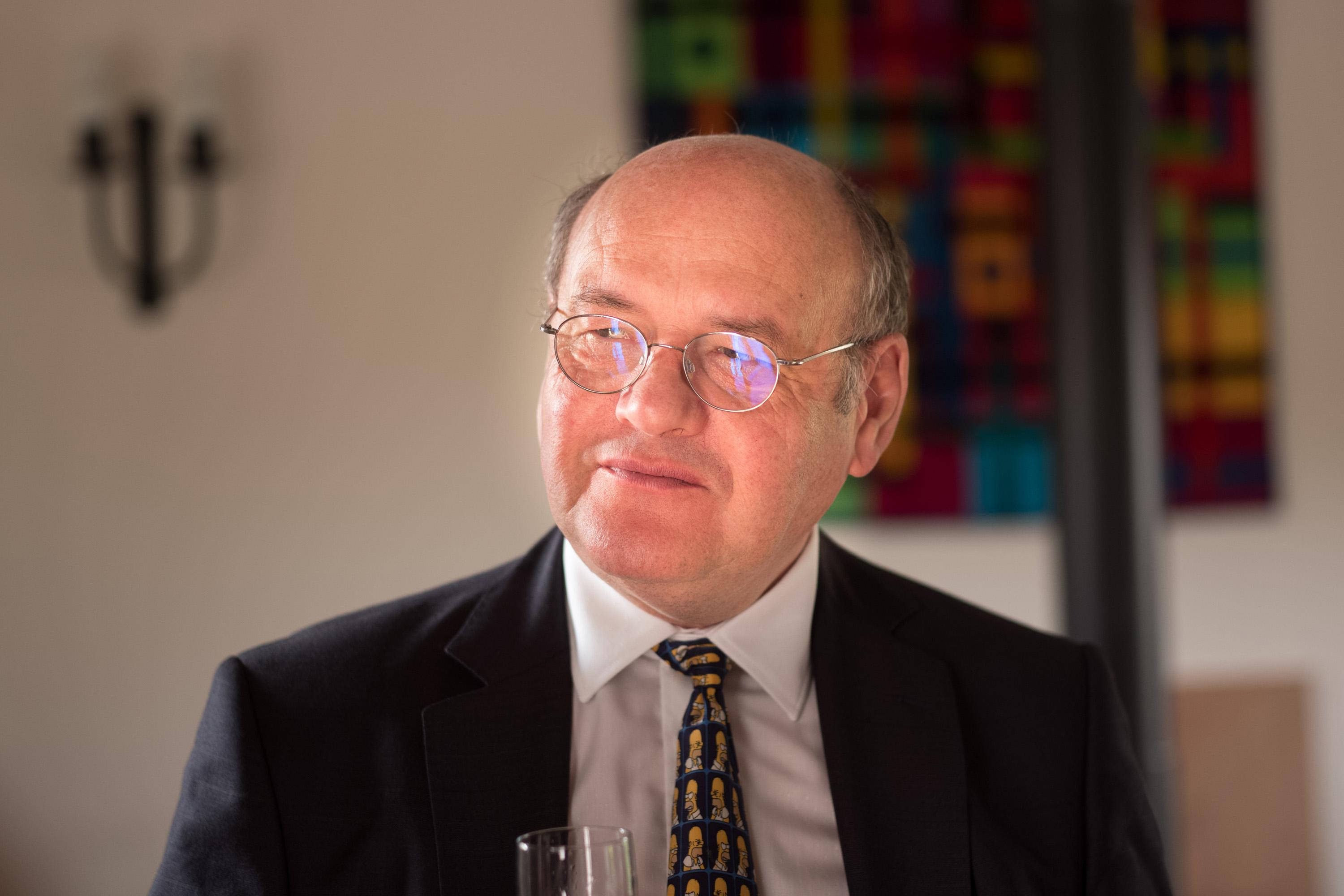 Photo of Hugh Colins. He is wearing a formal shirt and tie with a blazer.