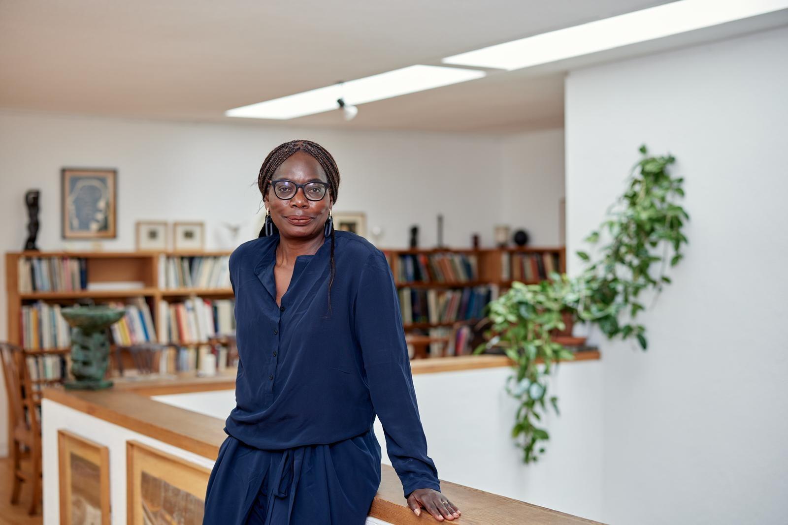 Black woman with glasses in a navy dress in a library