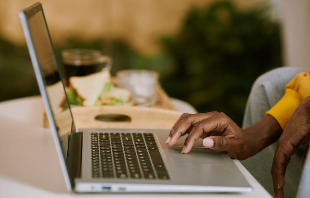 Photograph of a woman's hands working on a laptop.