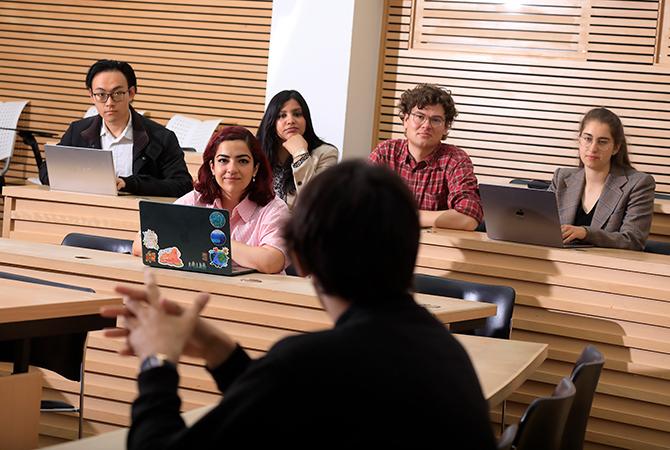 Students with laptops listening to a speaker in the Cube teaching space at the Faculty of Law