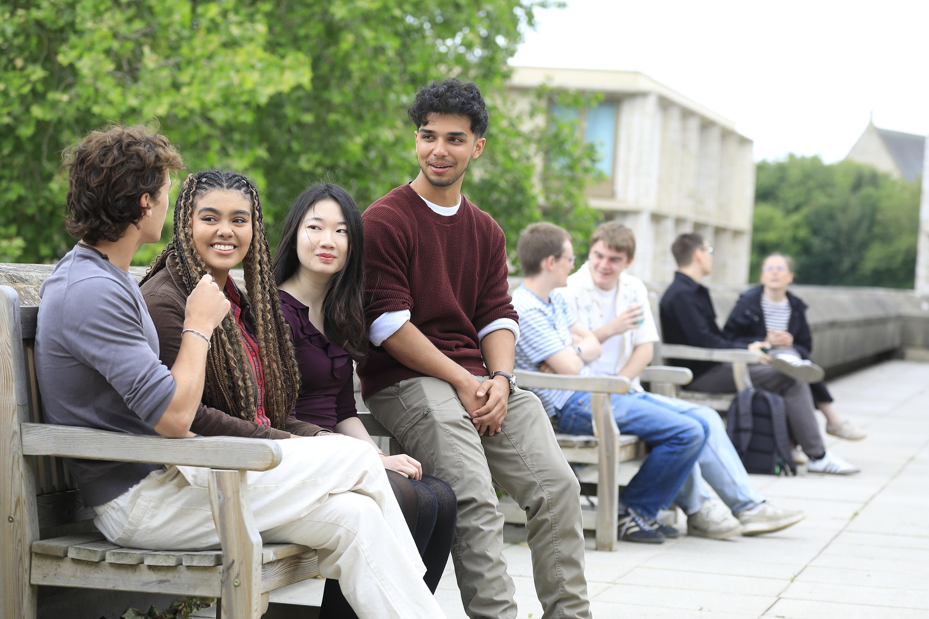 Students sitting on benches outside the St Cross Building