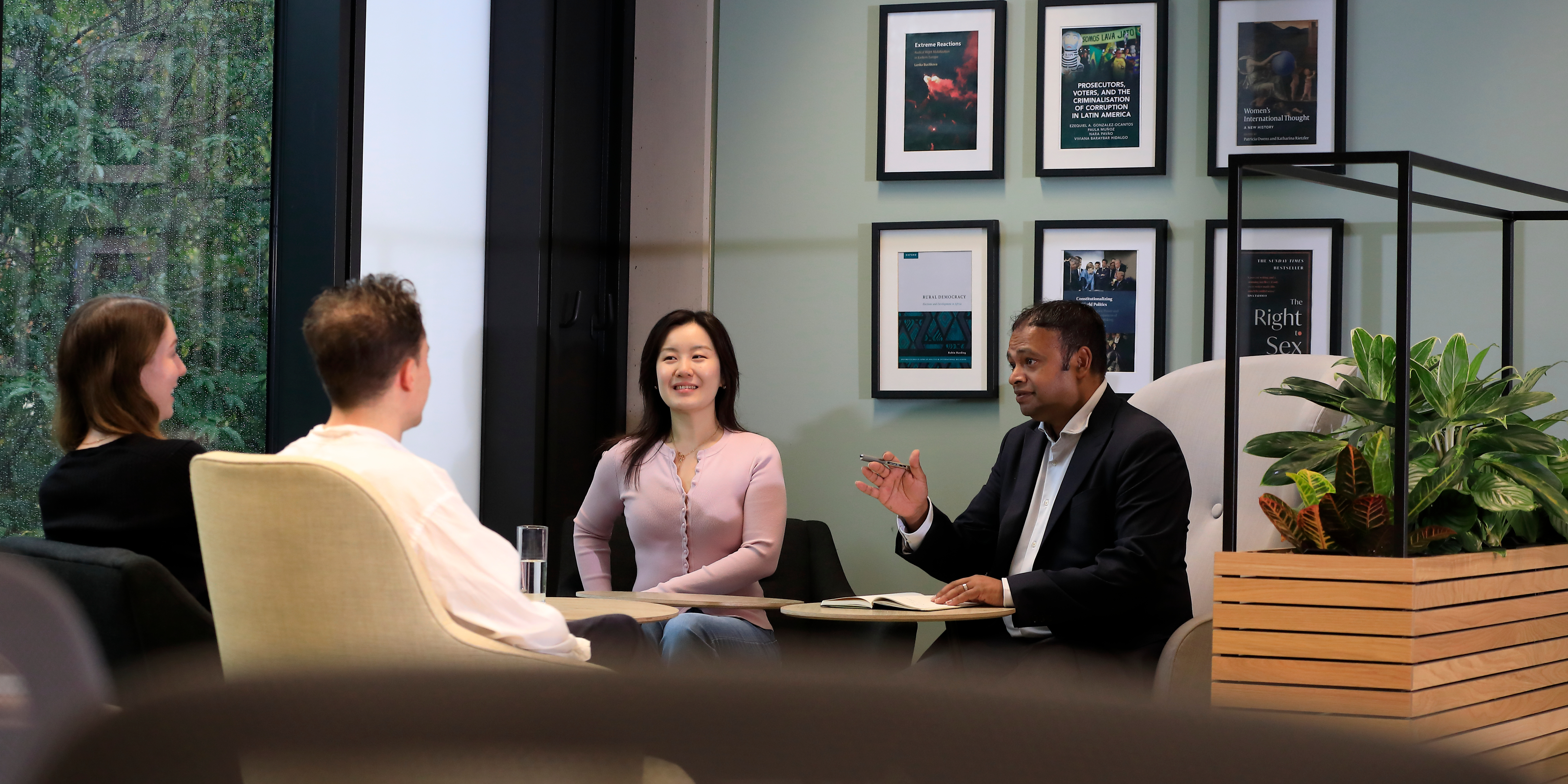A business man talking to students in a graduate study space