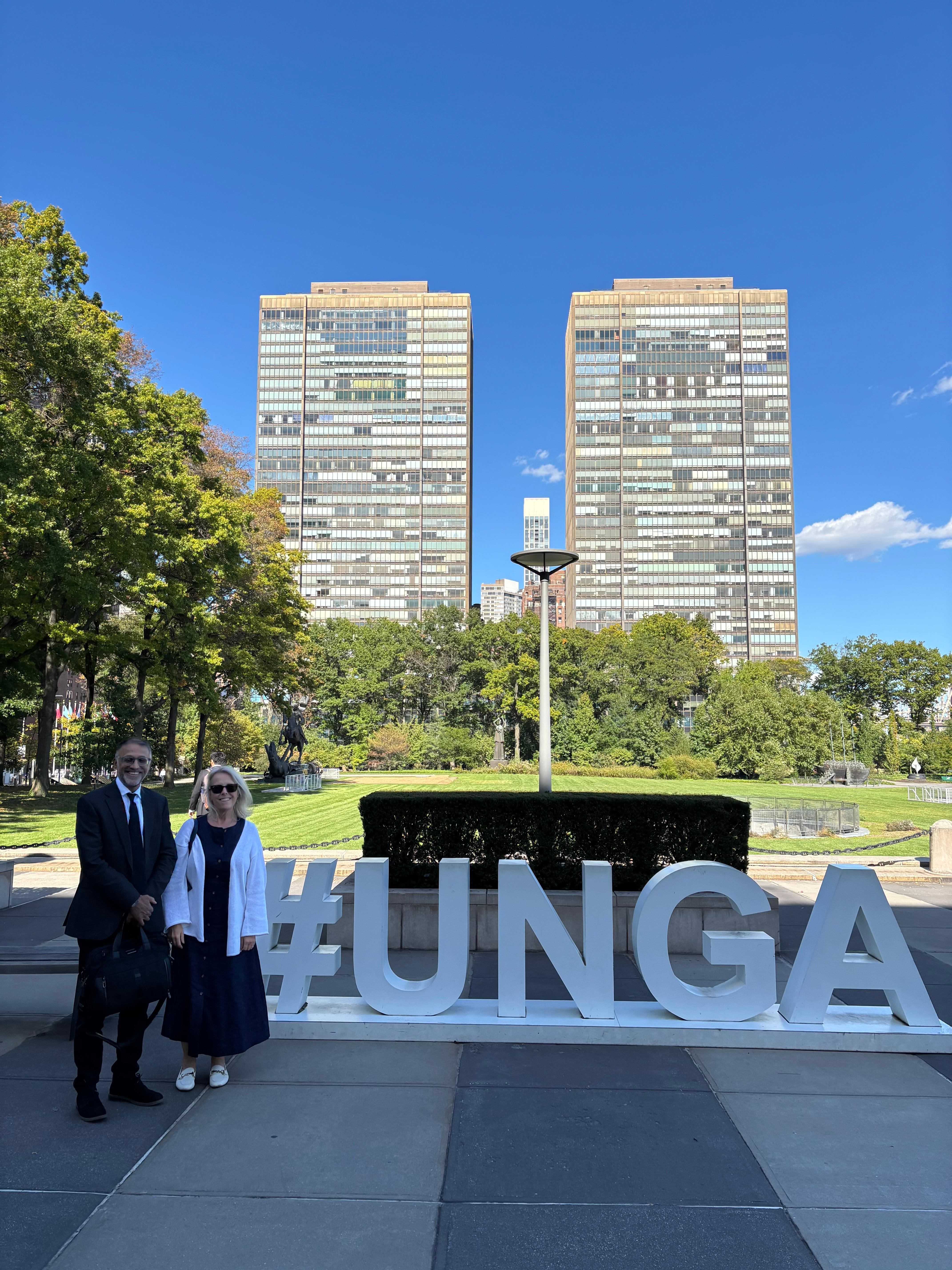 Professor Carolyn Hoyle and Lord Parvais Jabbar stand by a UNGA sign in New York